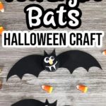 Two completed bats made with black flameless tea light candles on a gray wooden background with candy corn sprinkled around them. Text at top says Tea Light Bats Halloween Craft