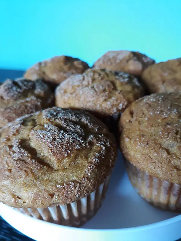 Close up side view of pumpkin muffins on a round white plate with a blue wall in the background.