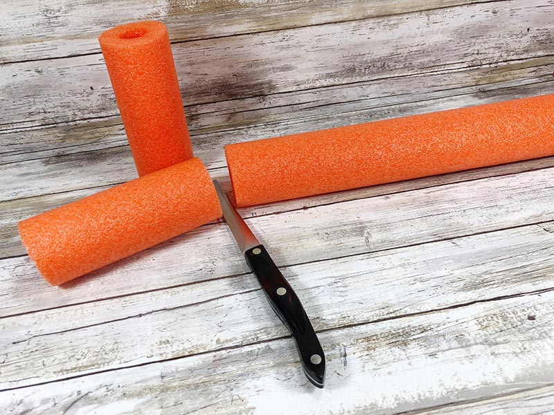 Knife cutting orange pool noodle into smaller pieces.