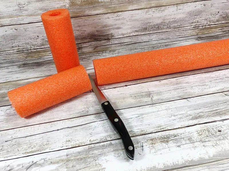 Knife cutting orange pool noodle into smaller pieces.