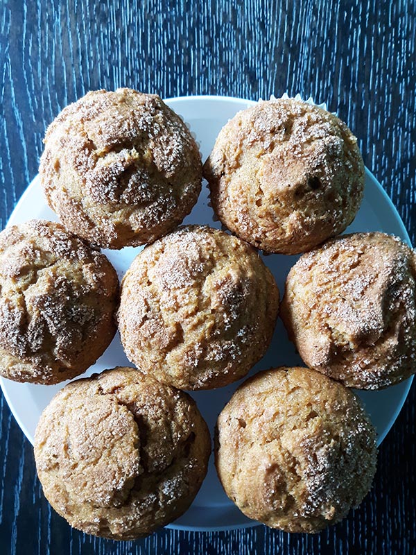 Top down view of seven gluten free pumpkin muffins on a white plate on a table.