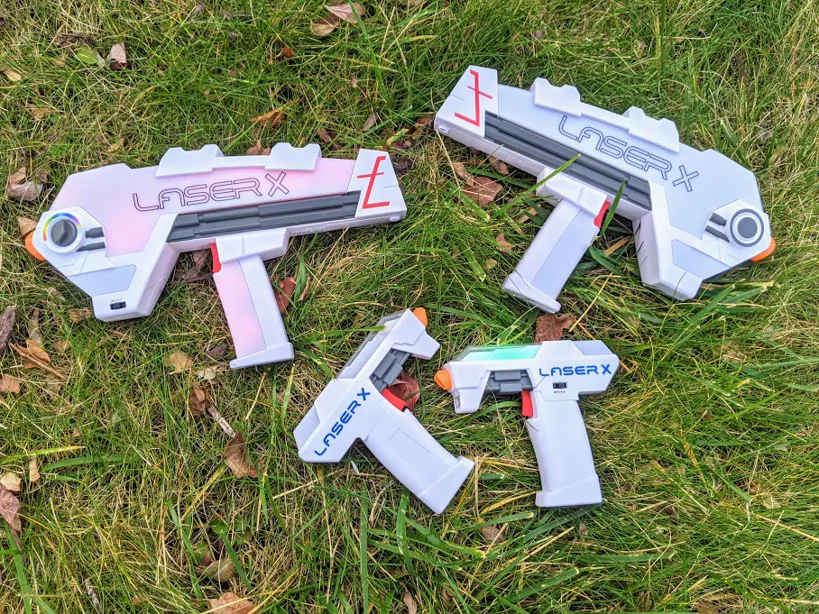 Pair of Laser X Evolution Blasters and a pair of Laser X Micro Blasters laying next to each other in the grass.