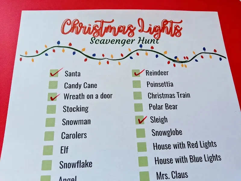 Close up view of printed out Christmas Lights scavenger checklist with a few items checked off with red marker.