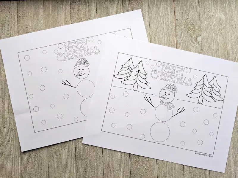 Snowman holiday card pages printed out and laying overlapped on gray wood background.