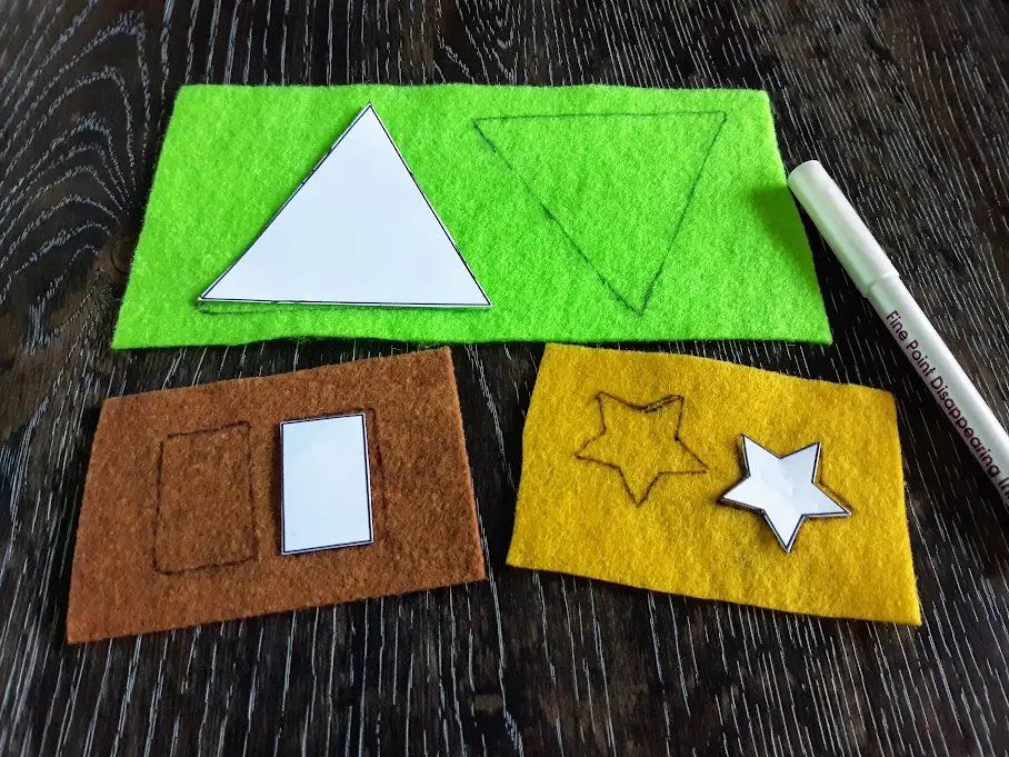 Printable templated being used to trace triangles on green felt, rectangles on brown felt, and stars on yellow felt.