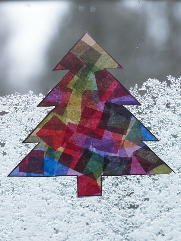 Close view of completed Christmas tree suncatcher hanging on snowy window.