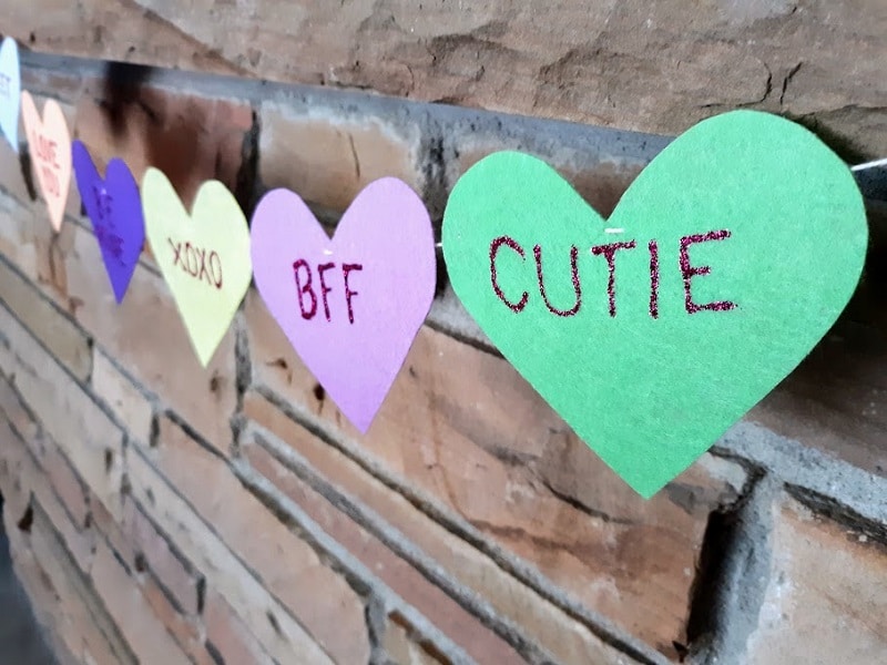 Close view from side angle of felt conversation heart banner hanging on mantel.