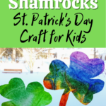 White and black text on green square on top half of image reads: Coffee Filter Shamrocks St. Patrick's Day Craft for Kids. Lower half of image shows one green and one rainbow tie dyed coffee filters cut into shamrock shapes in a bright wintery window.