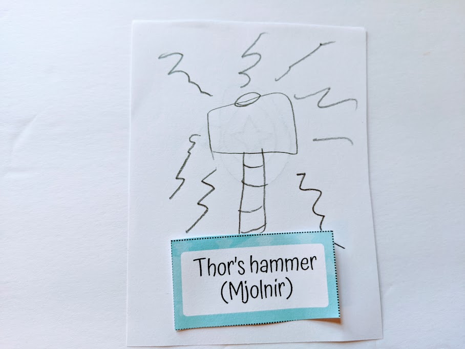 Child's drawing of Thor's hammer next to printable pictionary word card.