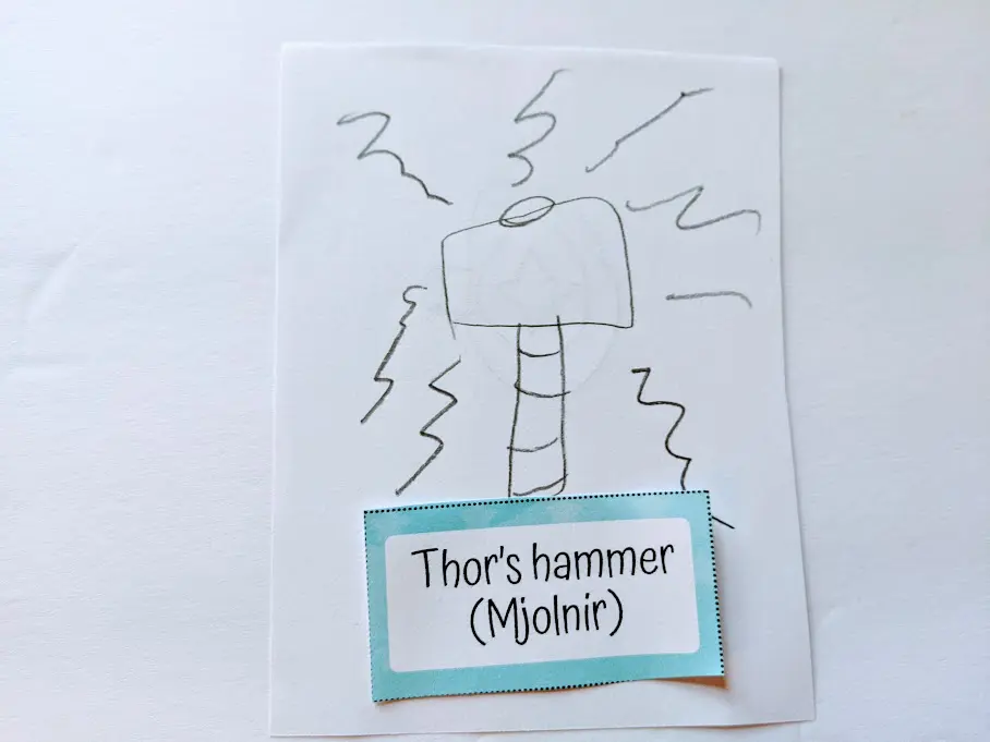 Child's drawing of Thor's hammer next to printable pictionary word card.