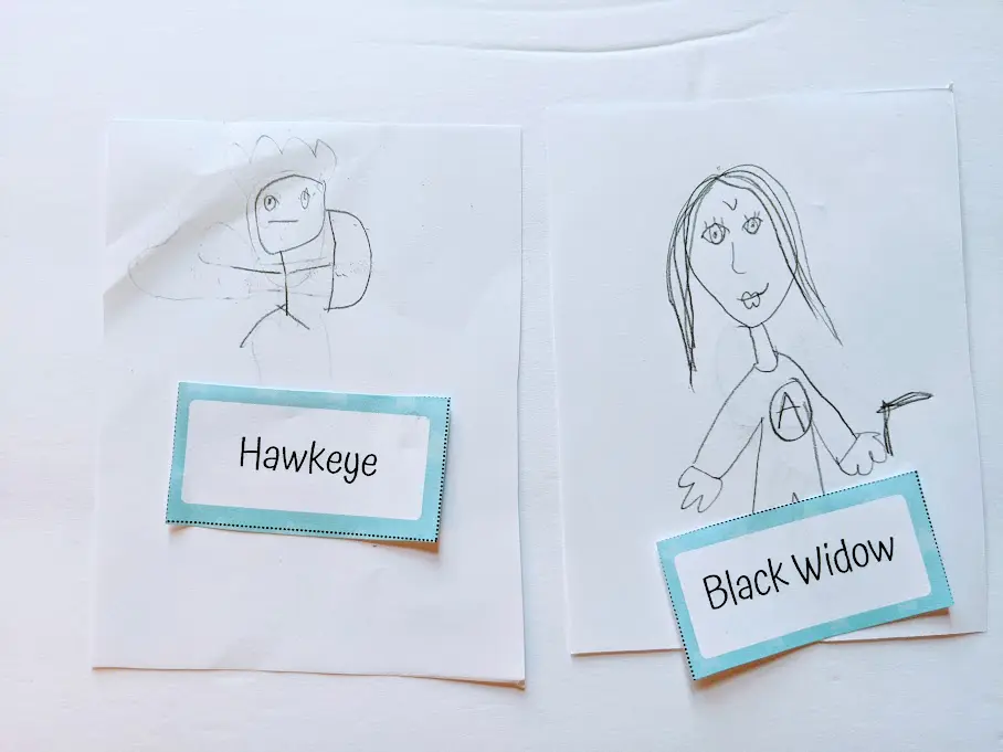 Kids' drawings of Hawkeye and Black Widow with the game word card by each picture.