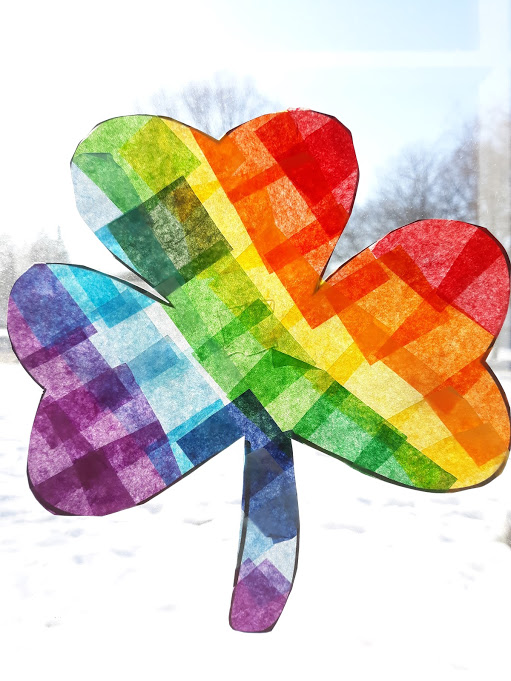 Tissue paper rainbow shamrock suncatcher in a brightly lit window.