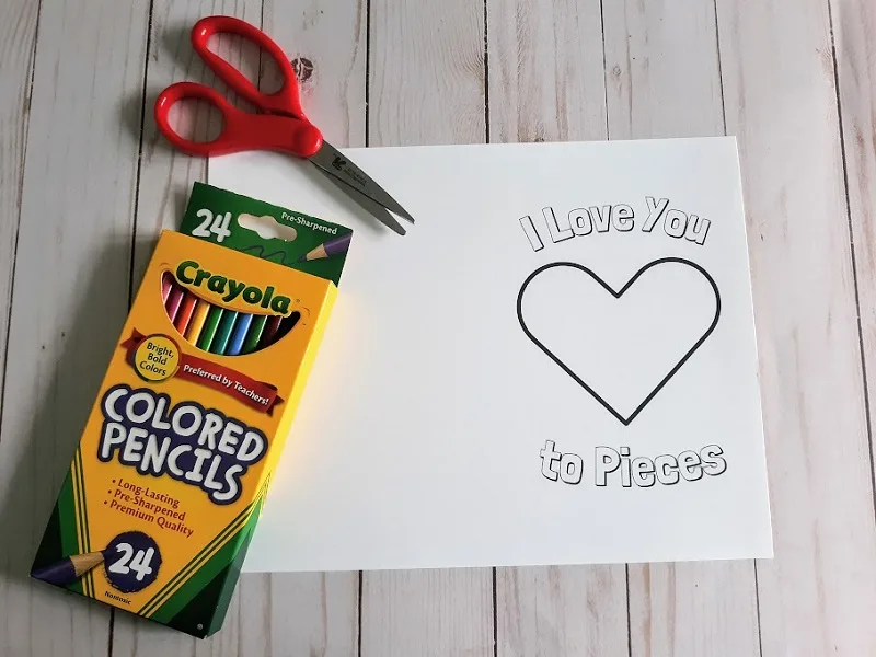 Love to Pieces card printed out and laying flat on table with red handled scissors and a box of colored pencils.