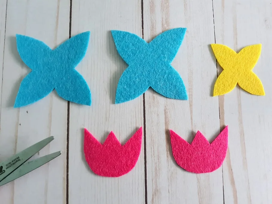 Two blue felt petal sections, one smaller yellow felt petal, and two pink felt tulip shapes cut out.