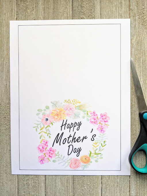 Overhead view of Mother's Day card printed out on white cardstock paper. Pair of scissors laying on the right side of it.