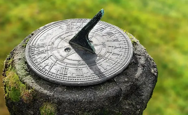 Shadow cast on a garden sundial on a stone pedastal.