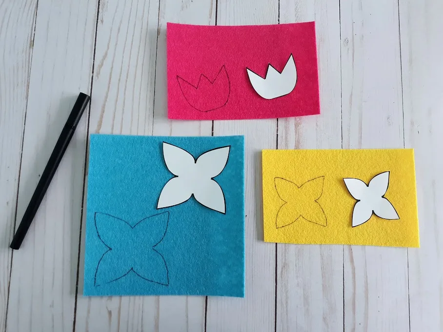 Tracing flower patterns on blue, yellow, and pink felt.