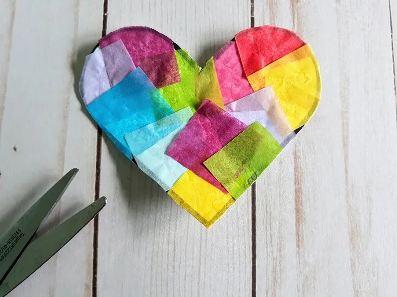 Close overhead view of completed small multicolored tissue paper heart suncatcher.