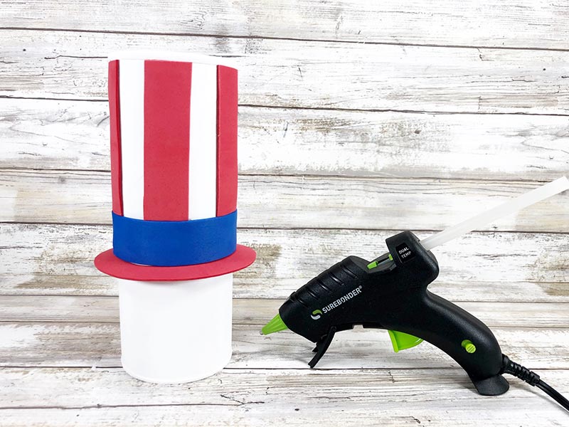 Red and blue craft foam pieces glued onto chip can painted white to make Uncle Sam's hat.