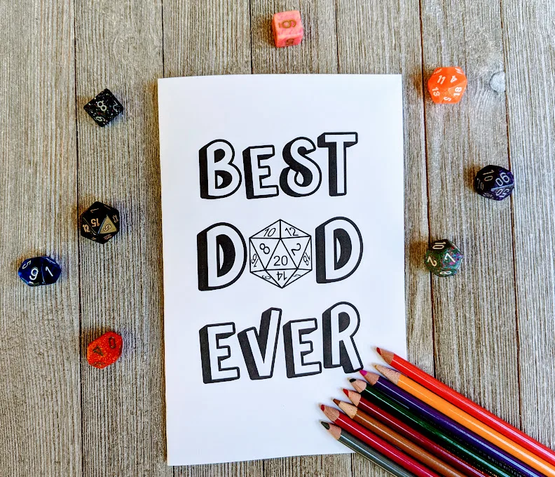 Overhead view of Best Dad Ever with a D20 in place of the A in Dad card printed out. Colored pencils lay lined up by the bottom right corner of the card. Assorted polyhedral dice for tabletop games are scattered around the card.