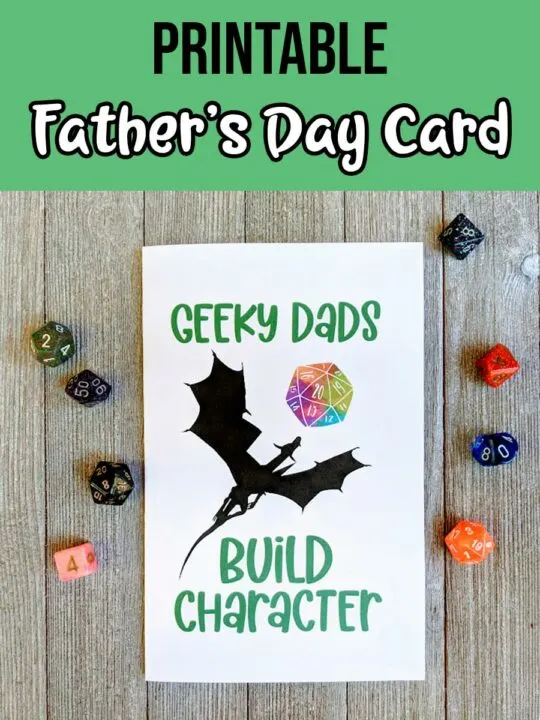 Black and white text on a green background at top says Printable Father's Day Card. Photo of printed out card that says Geeky Dads Build Character with a dragon and watercolor D20. Assorted dice are placed around the card.