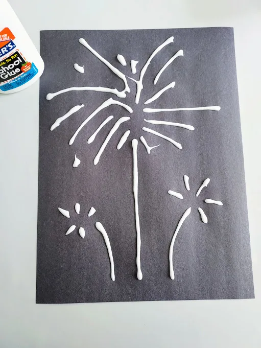 White glue lines in fireworks design on black construction paper.