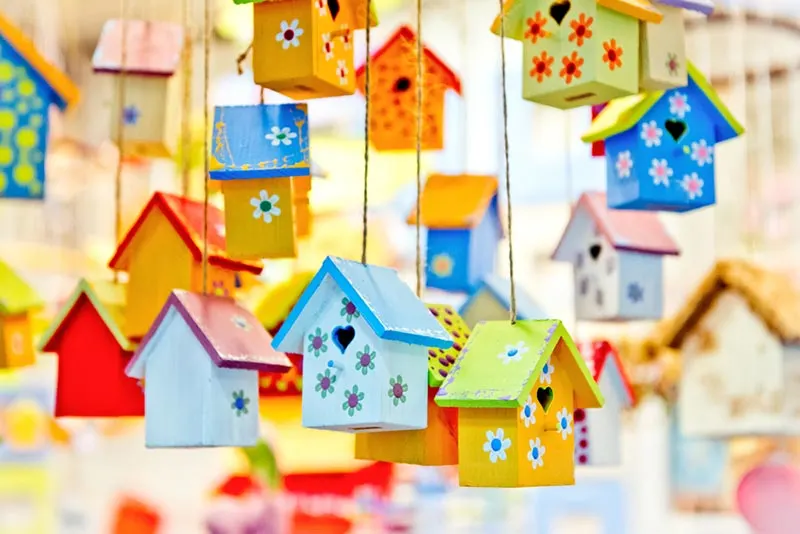 Numerous hanging wooden birdhouses painted with bright, vibrant colors.