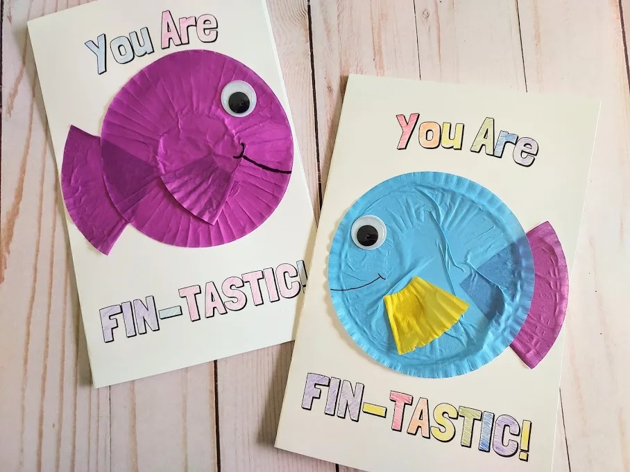Two completed printable cards that say You Are Fin-Tastic. Words are colored in. Left card has a purple fish made from paper baking cups. Card on the right has a blue, purple, and yellow cupcake liner fish.