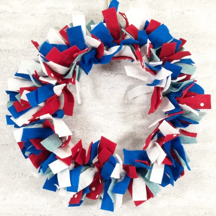 Completed red white and blue felt wreath hanging on wall.