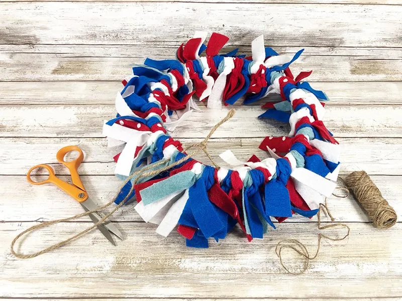 Finished red, white and blue felt wreath laying face down to add twine hanger to the back.