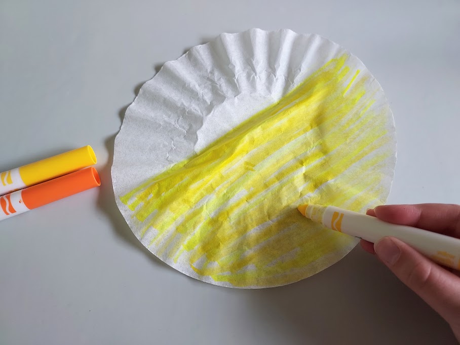 Coloring a coffee filter with yellow washable marker.