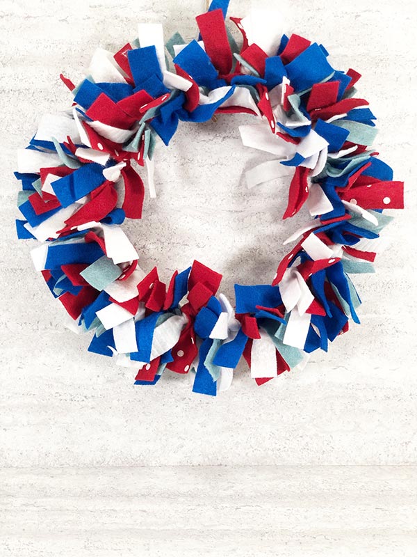 Completed red, white and blue no sew felt wreath hanging up for a festive Fourth of July decoration.