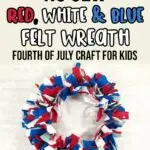 A picture of a felt wreath made with red, white, dark blue, and light blue felt strips hanging against an off white brick wall. Above wreath text in black, red, white, and blue says No Sew Red, White & Blue Felt Wreath Fourth of July Craft for Kids.