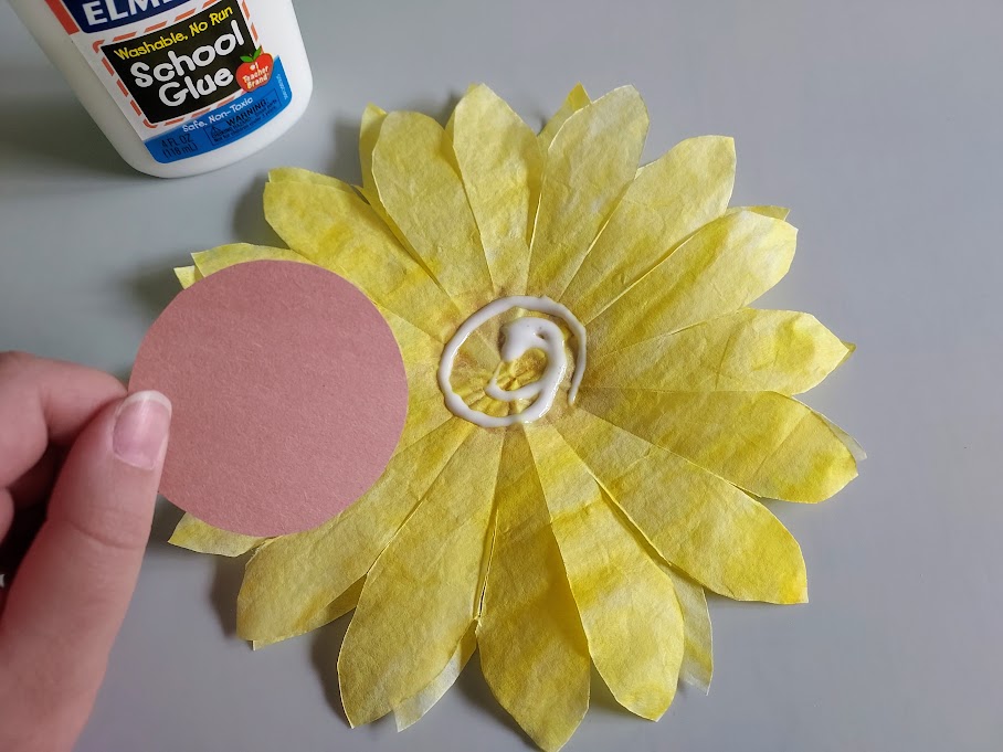 Gluing brown construction paper circle to center of coffee filter sunflower petals.