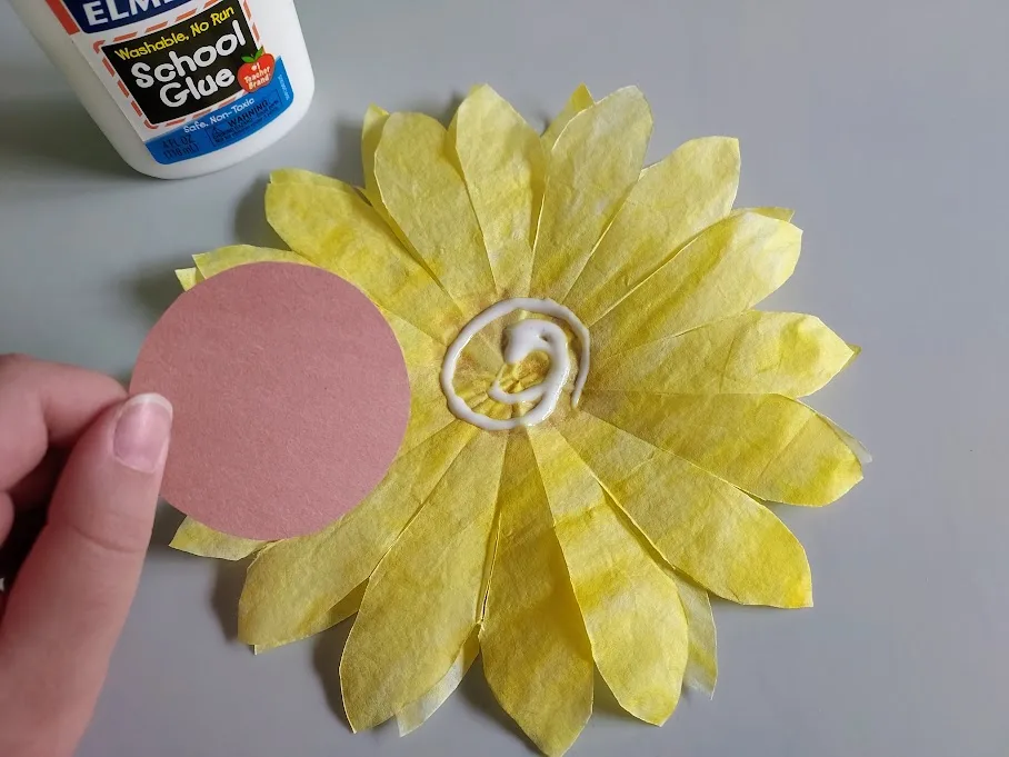 Gluing brown construction paper circle to center of coffee filter sunflower petals.