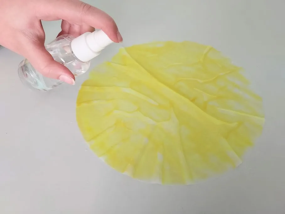 Spritzing yellow colored coffee filter with water.
