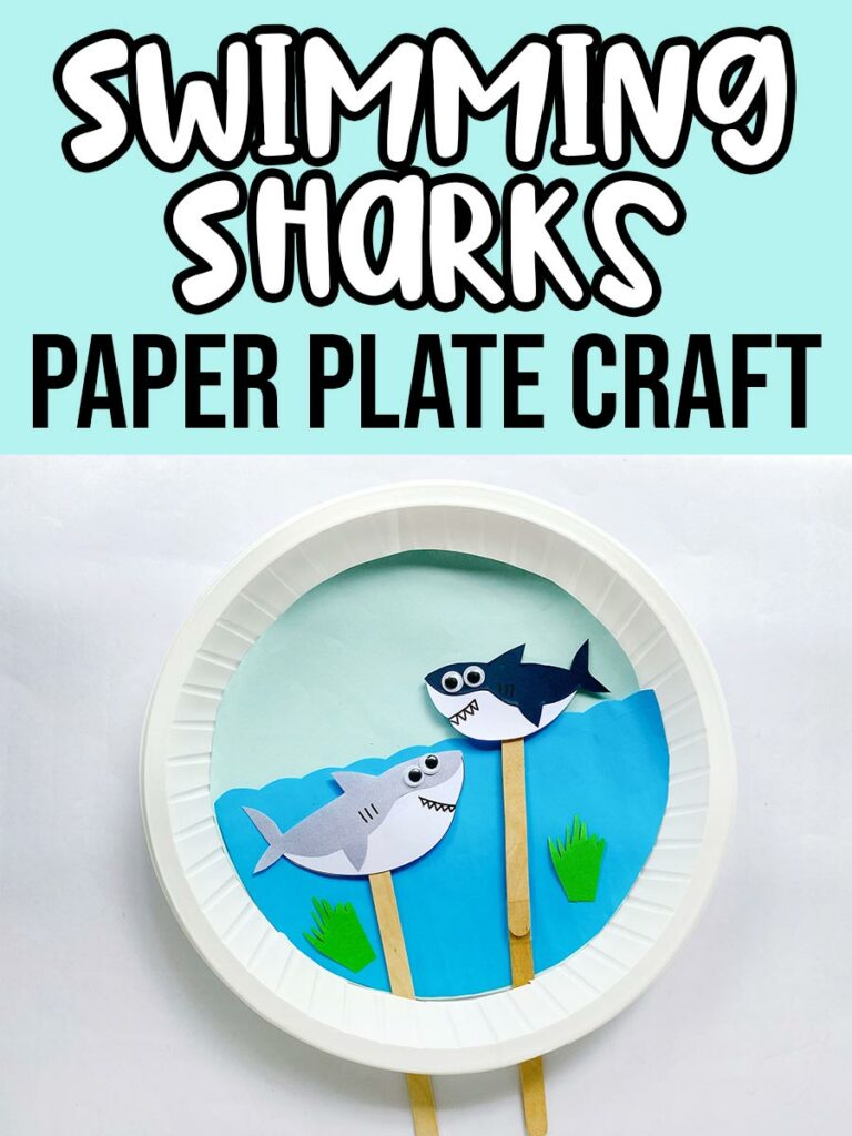 White and black text on light blue background at top says Swimming Sharks Paper Plate Craft. Below text is a photo of a completed craft using a paper plate as a backdrop and decorated to look like the ocean and two paper shark puppets on popsicle craft sticks move around through slit in the plate.