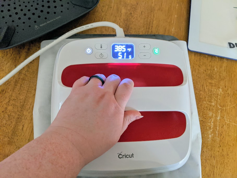 White woman's hand holding EasyPress 2 in place while applying infusible ink.