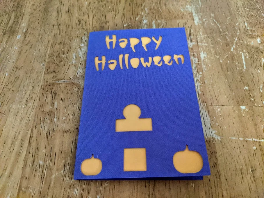 Halloween card closed with orange insert attached inside and showing through cutouts.