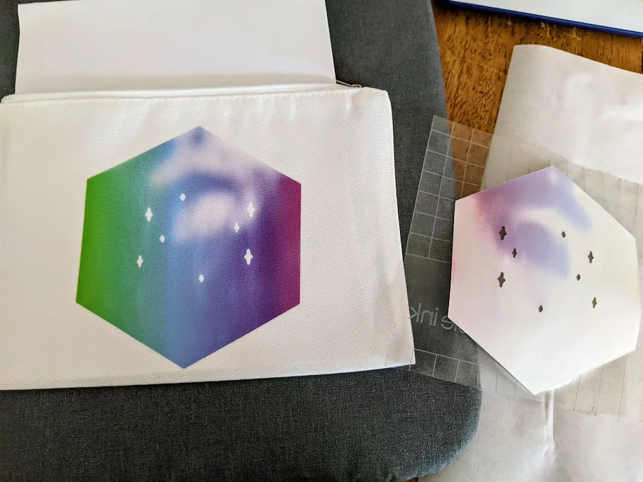 Infusible ink transfer sheet applied to cosmetics bag. Transfer sheet laying next to project and can see not all of the ink transferred at the top of the design.