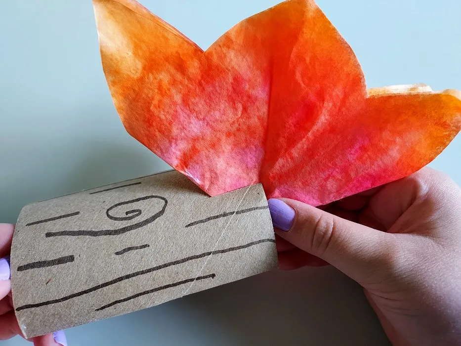 Close up view showing how to slide cut coffee filter into slit made on cardboard tub log.