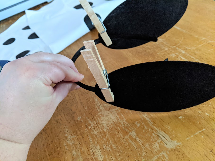 Clothespins clipping black felt ears to thin black headband before hot gluing.