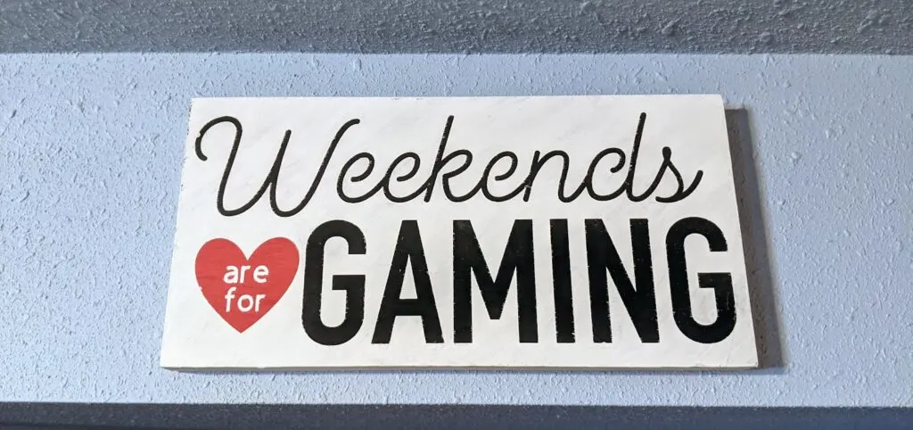Handpainted sign that says Weekends are for Gaming hung on a light blue wall.