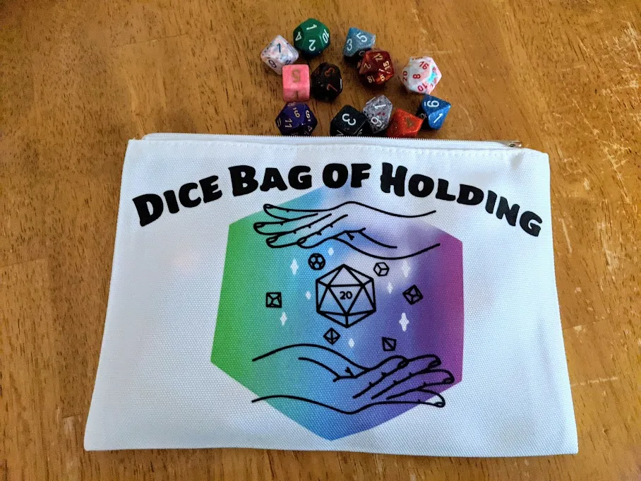 Overhead view of completed dice bag project. Assorted dice are spilling out on the table from the opening of the dice bag.