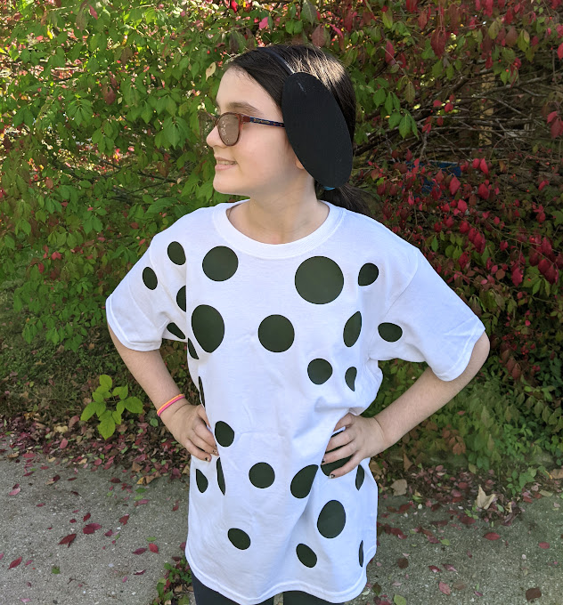 White tween girl standing outside with head turned to the side showing felt ears while wearing homemade Dalmatian costume.