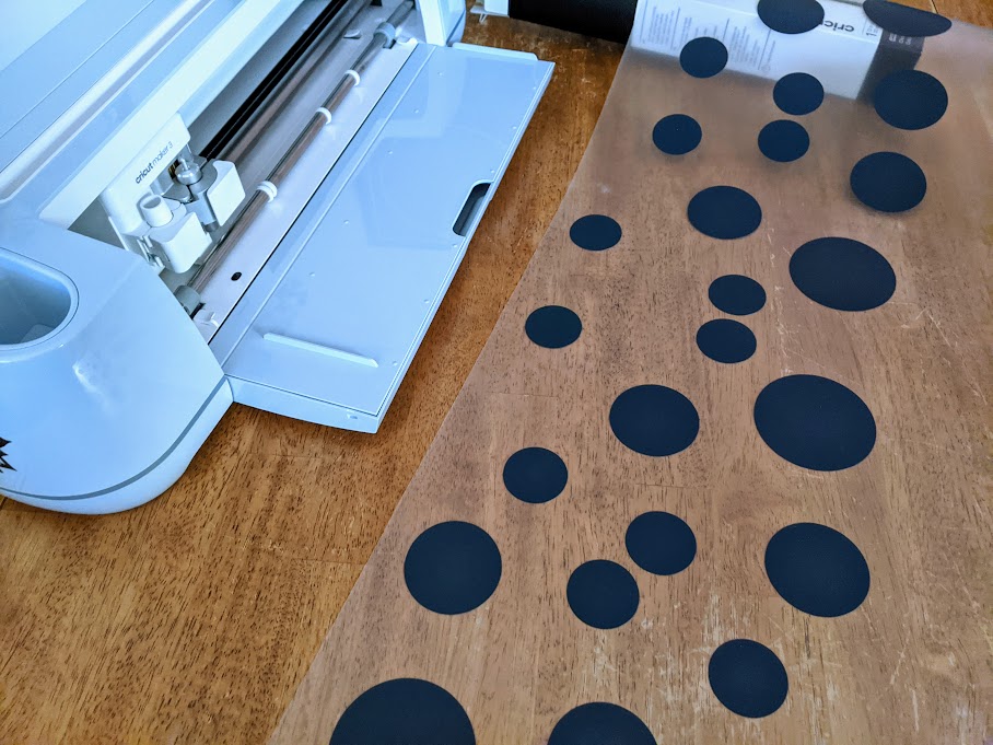3 foot long liner of smart iron on vinyl with excess material removed showing all the black spots on the liner. Liner laying next to Cricut Maker 3 machine on table.
