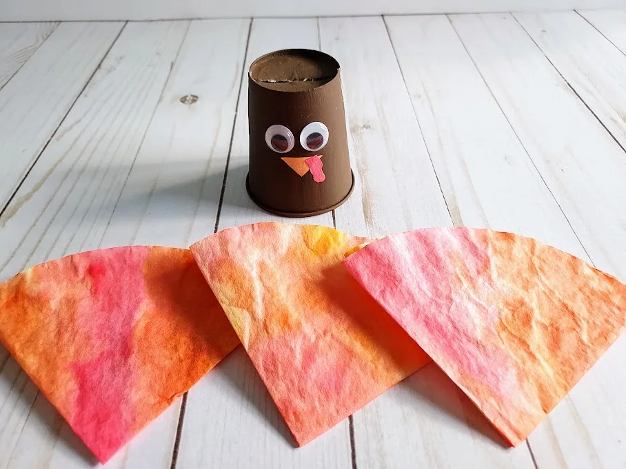 Turkey cup body with colored and folded coffee filters in front of it to be used as its feathers.