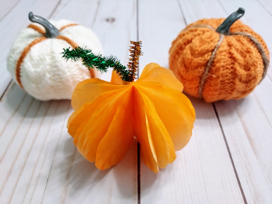 3D coffee filter pumpkin standing up next to yarn pumpkins.