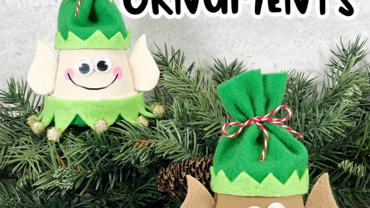 Black text at top reads Elf Clay Pot Ornaments. Black text at bottom reads Christmas Craft for Kids. Two finished elf clay pot crafts arranged by a garland of evergreen. One elf is painted with lighter skin tone and one is painted with darker skin tone. They are wearing green felt hats.