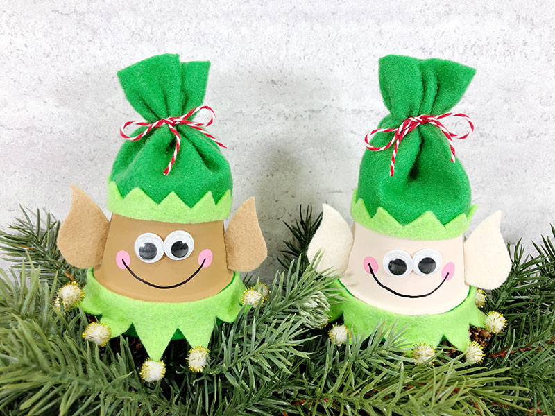 Two finished clay pot elf Christmas crafts with smile added using black marker.